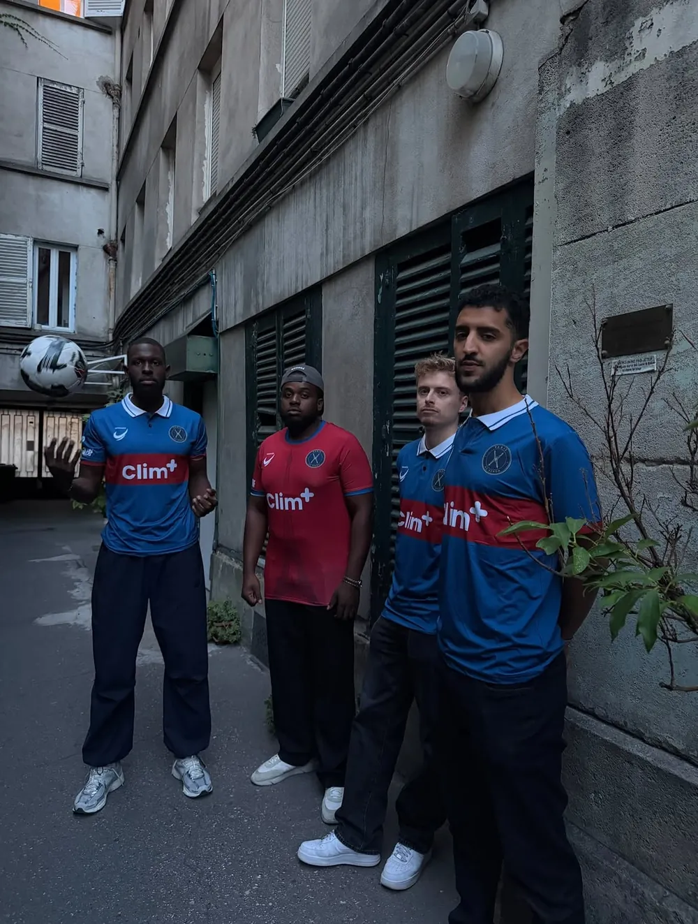 Four AS Xenon players in a Paris courtyard wearing blue and red sublimated football jerseys with white polo collars and a Clim+ sponsor band across the chest